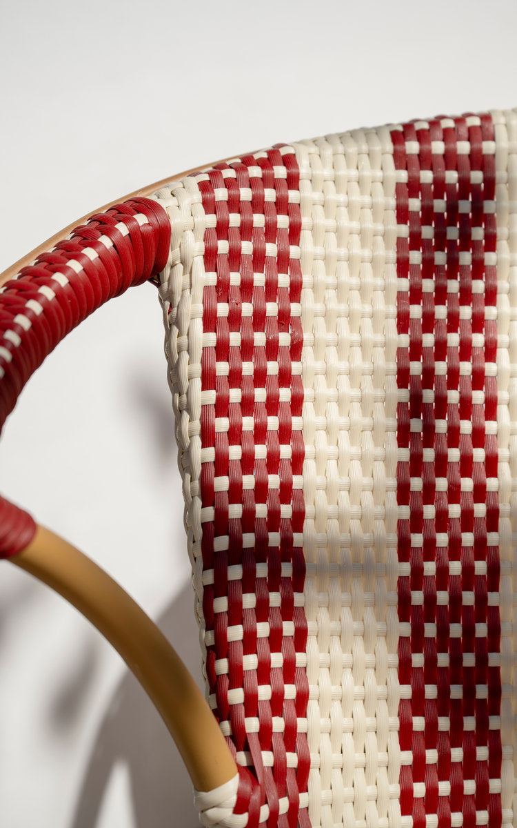 Dette er et nærbillede af Madeleine Udendørs bænk i almond aluminum frame striped ivory burgundy. Stribet flet og omviklet armlæn i dagslys.