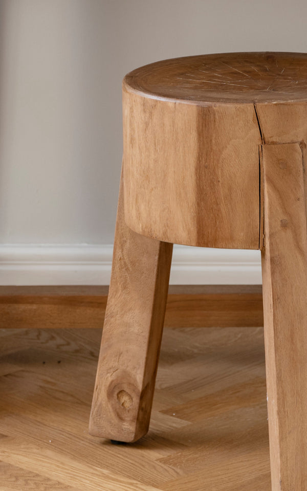 Dette er et nærbillede af Roger Skammel i teak indoor. Detalje af det massive teaksæde og tre kraftige vinklede ben.
