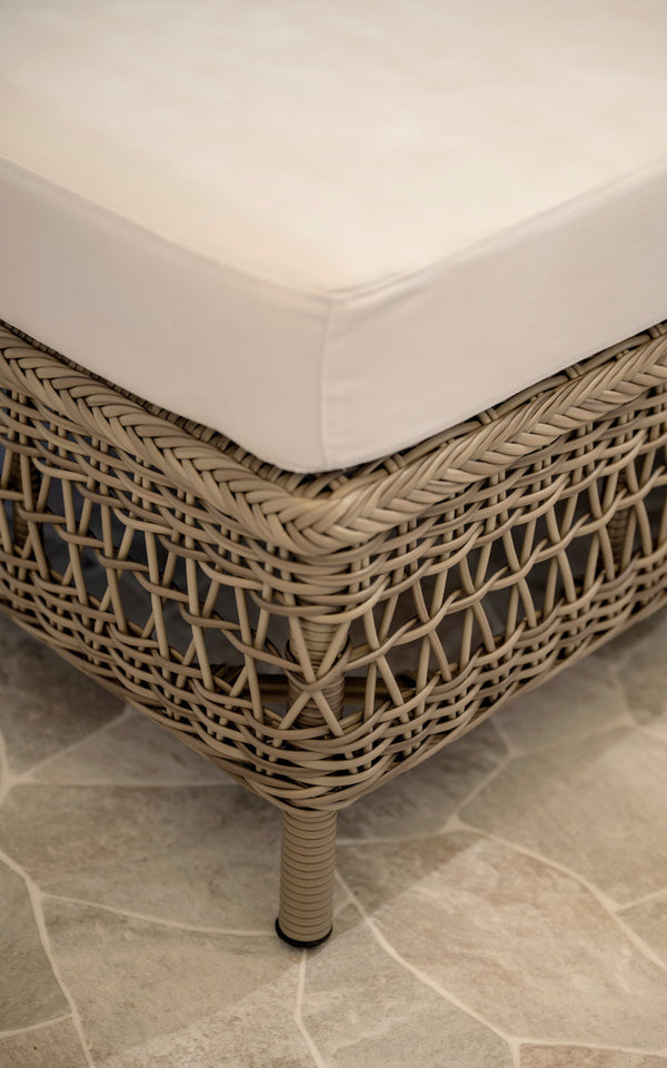 Dette er et nærbillede af Mona Udendørs modulsofa-Pouf Module i antique grey artfibre aluminium. Flettet pufkant med hvid pude.