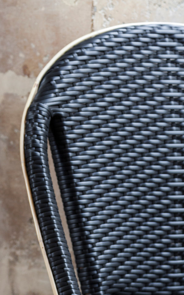 Dette er et nærbillede af Sofie Spisebordsstol i black artfibre skin on rattan frame. Detalje af den flettede tekstur og stelkonstruktion.