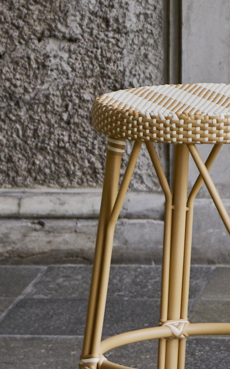 Dette er et nærbillede af Simone Skammel i striped honey ivory ArtFibre Skin on Rattan frame. Sædedetalje mod en ru stenvæg.