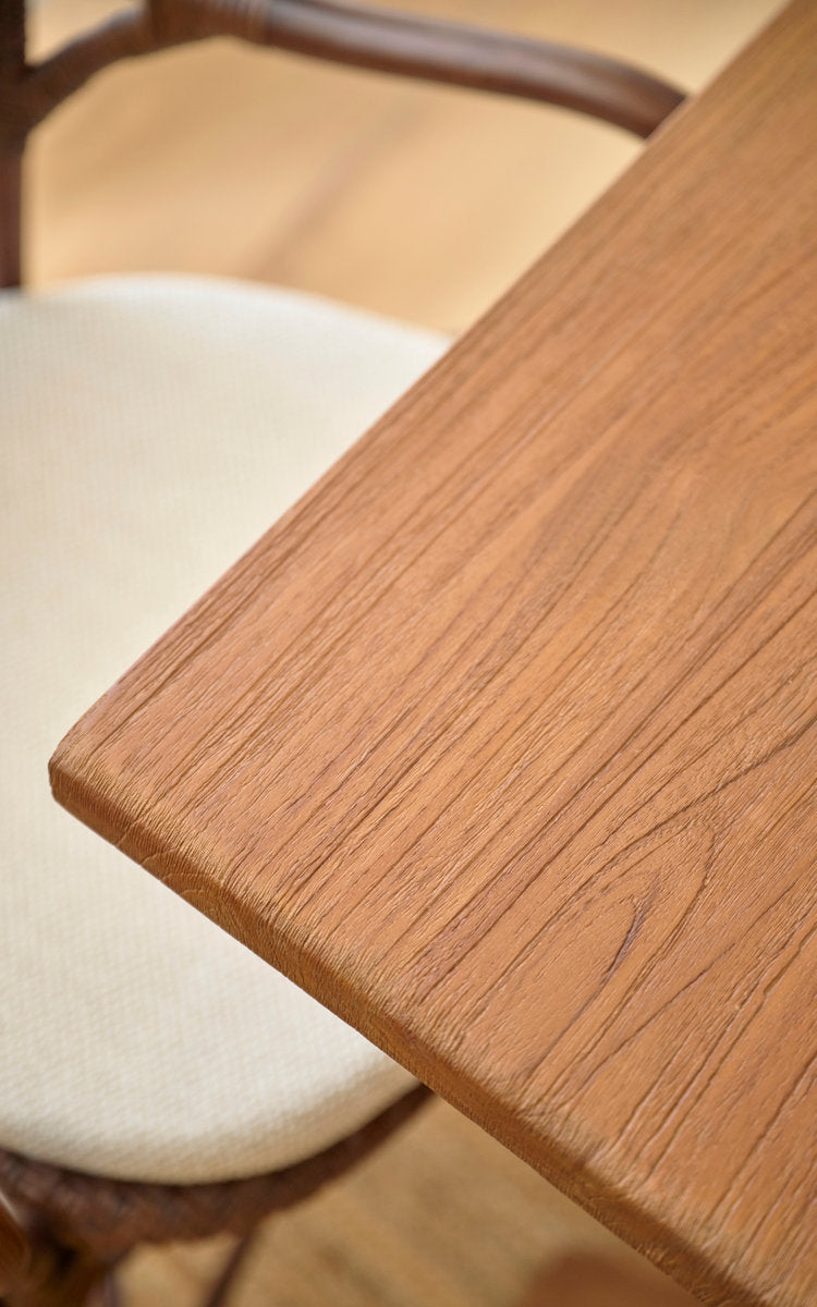 Dette er et nærbillede af Hugo Teak spisebord 140x90 cm i teak indoor. Glat kant af teakbordplade ved en rattanstol.