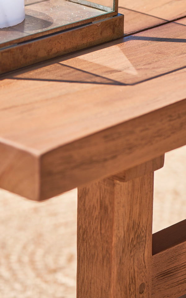 Dette er et nærbillede af Julian Teak Lounge Table 140x55 cm i teak outdoor. Den tykke solide teakkant og de robuste bensamlinger er vist.