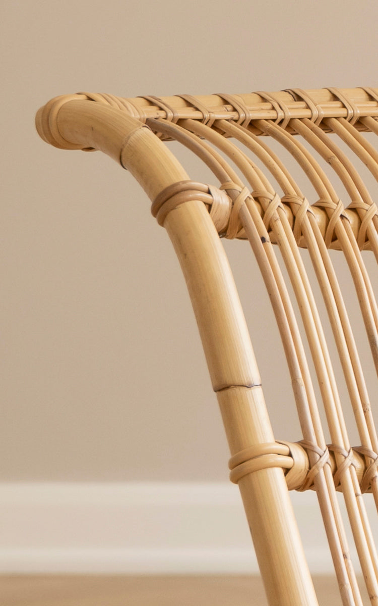 Dette er et nærbillede af Paris Lænestol i polished natural rattan. Detalje af det buede rattanstel og buede sædelameller.
