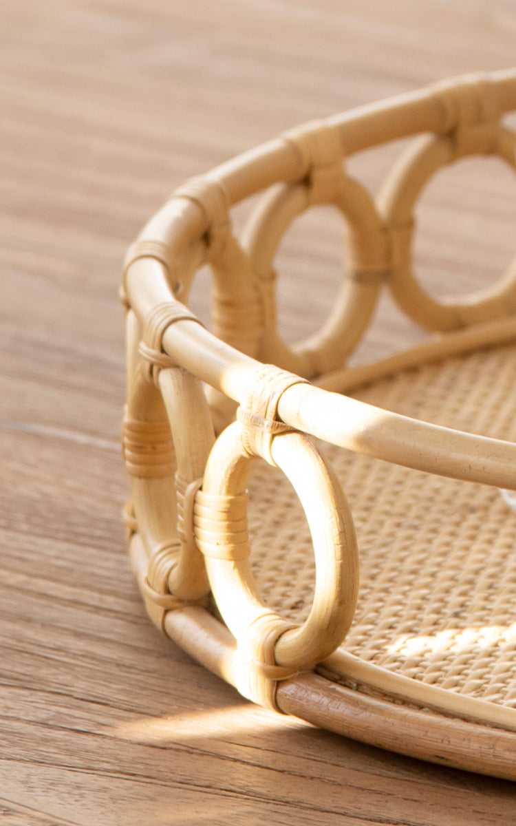Dette er et nærbillede af Mira Tray i natural rattan. Detalje af den cirkulære ringkant og den flettede spanskrørsbase på den runde bakke.