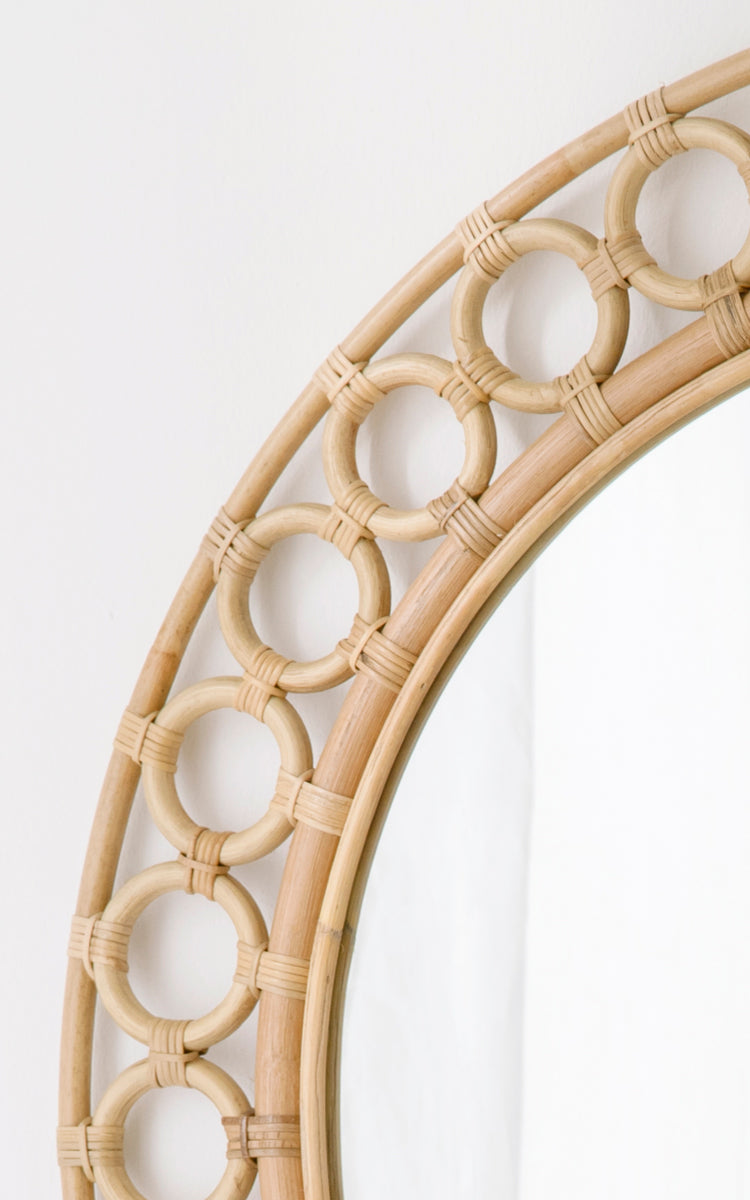 Dette er et nærbillede af Mira Mirror i natural rattan. Detalje af den cirkulære rattanringkant, der rammer det runde spejl.