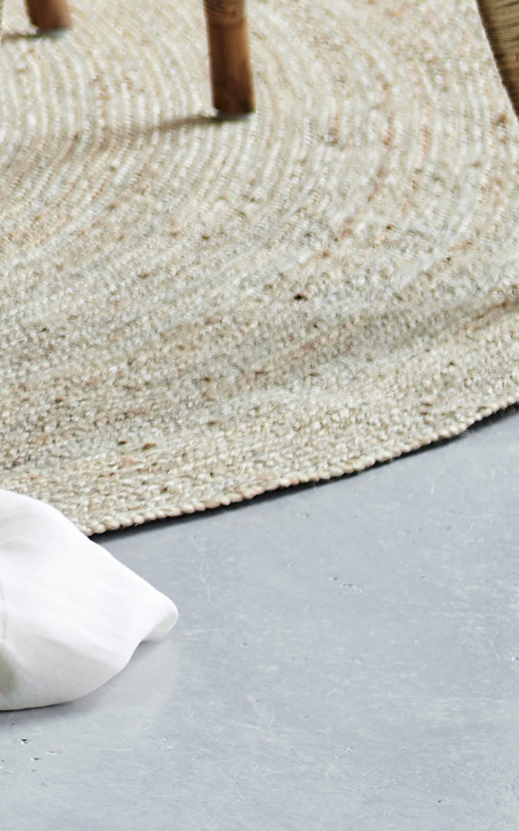 Dette er et nærbillede af Jute Carpet Ø280 i grey jute. Den tætvævede tekstur og den afrundede kant er vist på et betongulv.
