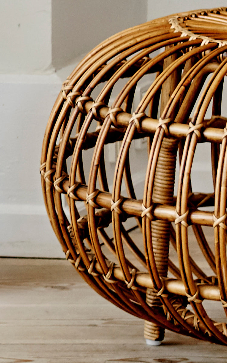 Dette er et nærbillede af Ottoman Large i polished antique rattan. Detalje af det store åbne rattanbur med buede ribber på trægulv.