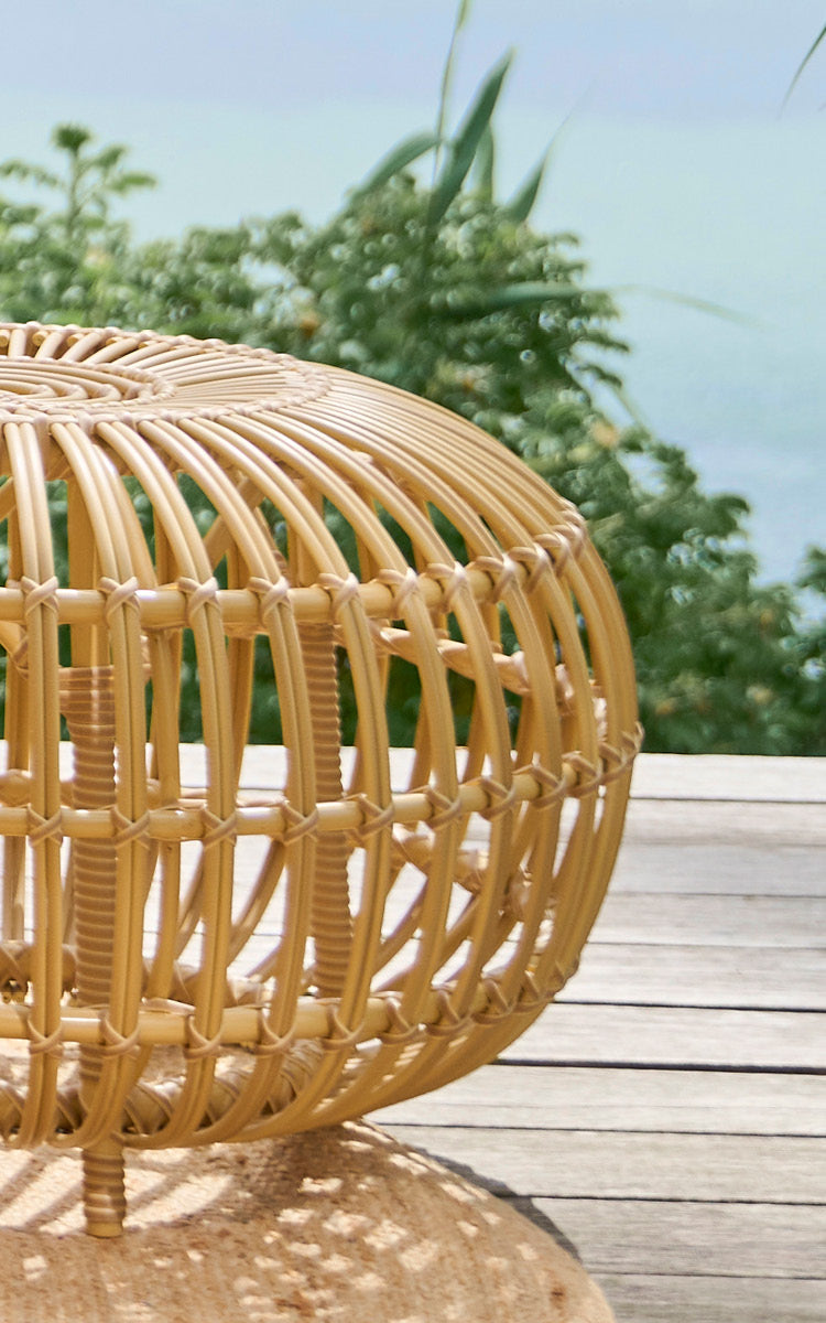 Dette er et nærbillede af FA-E16-NU Ottoman Exterior i natural aluminium artfibre. Detalje af den flettede ArtFibre-puf med buede ribber på et dæk.