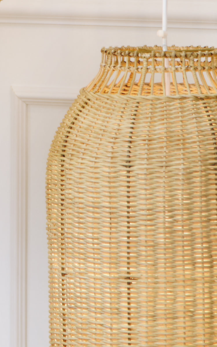 Dette er et nærbillede af Kou Lampeskærm i natural core weave rattan frame. Den tætvævede lanterneform og det varme lys er fremhævet.