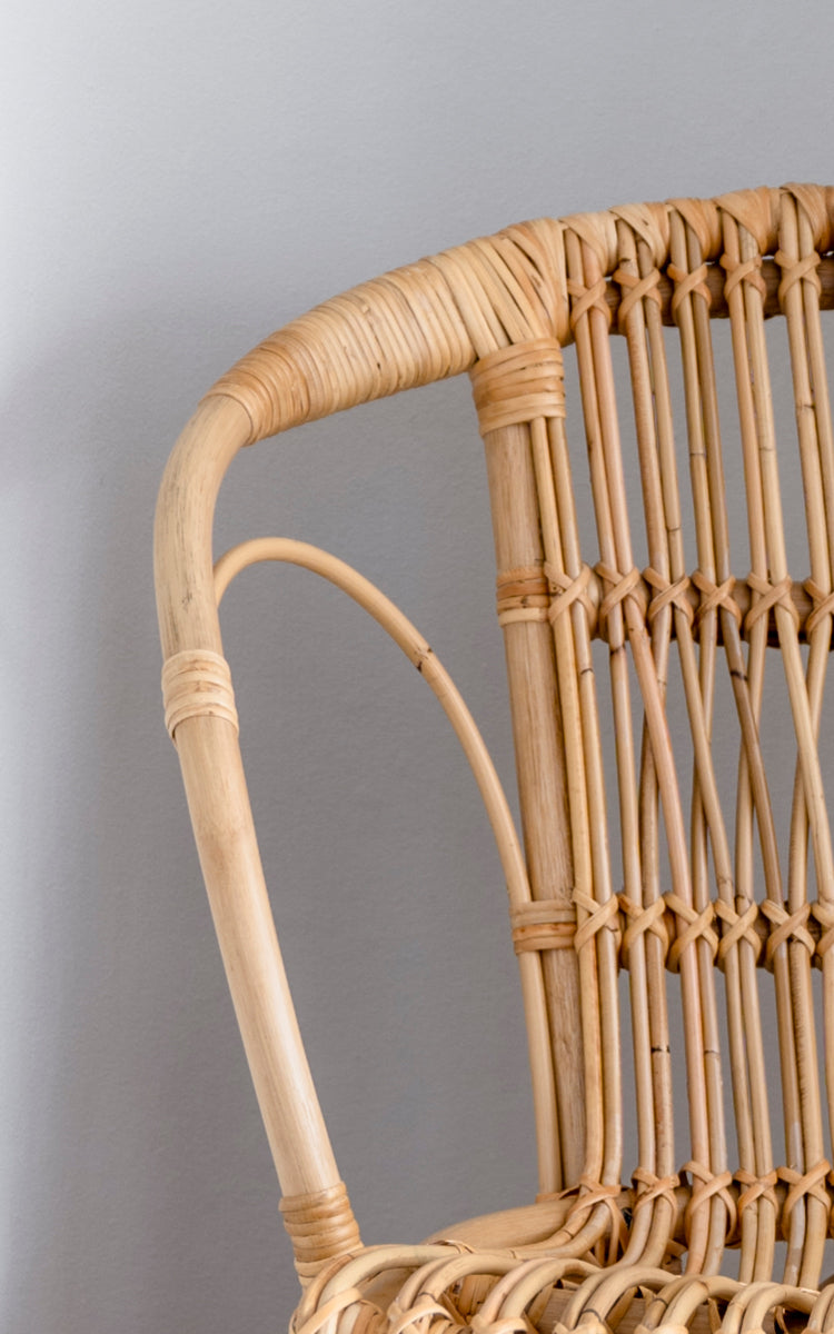Dette er et nærbillede af Robert Spisebordsstol i polished natural rattan. Detalje af den naturlige buede rattan-arm og spindelryg.
