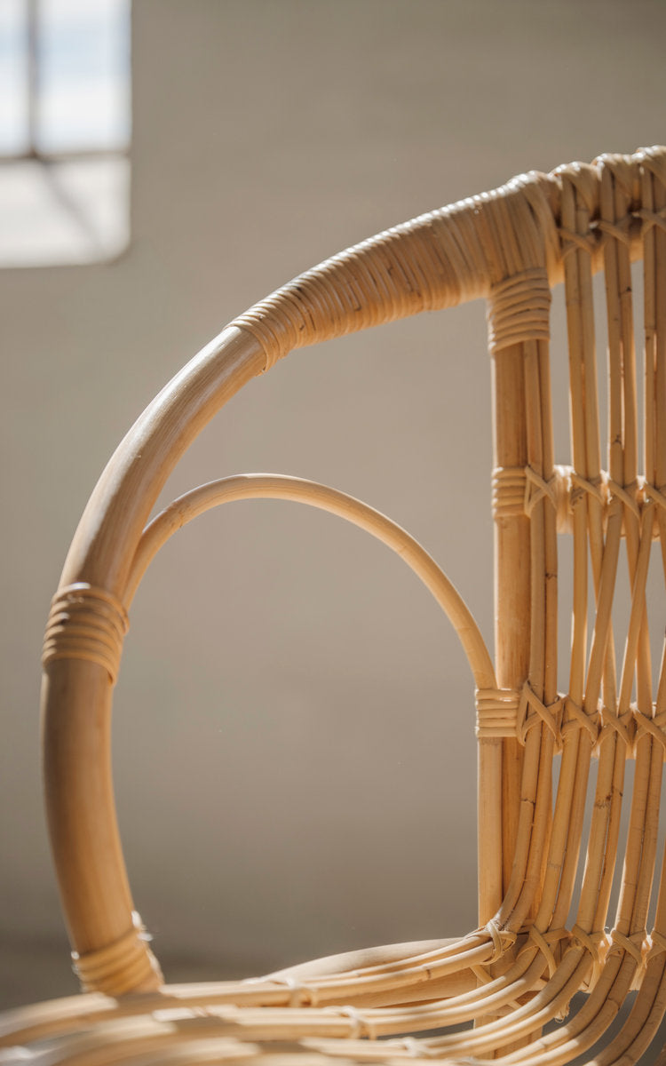 Dette er et nærbillede af Robert Spisebordsstol i polished natural rattan. Buet armlæn og omviklede rattandetaljer.