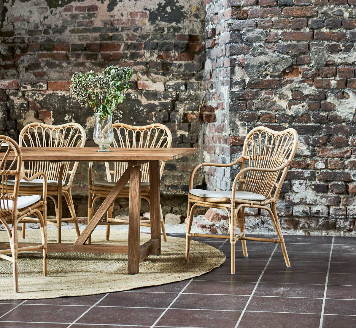 Dette er et livsstilsbillede af Margret Spisebordsstol i natural rattan. Industriel loft med synlig murstensvæg og jutetæppe.