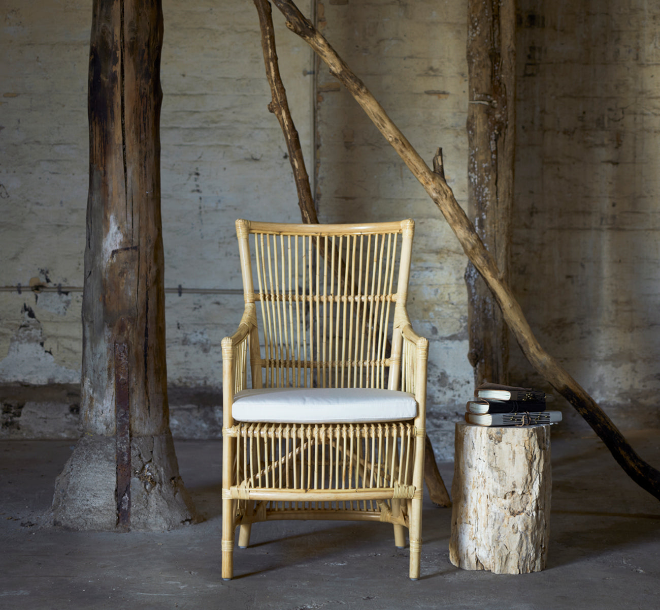 Dette er et livsstilsbillede af Davinci Spisebordsstol i natural rattan, i et lyst interiør med hvide panelvægge og sildebensgulv.