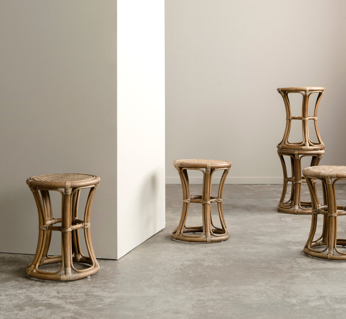 Dette er et livsstilsbillede af Bella Skammel i antique rattan, i et lyst interiør med hvide panelvægge og sildebensgulv.