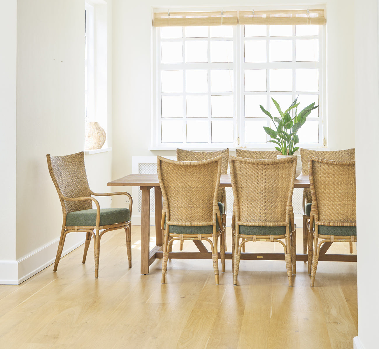 Dette er et livsstilsbillede af Melody Dining Armchair i antique rattan. Seks stole ved et teakbord i et lyst rum med egegulv.