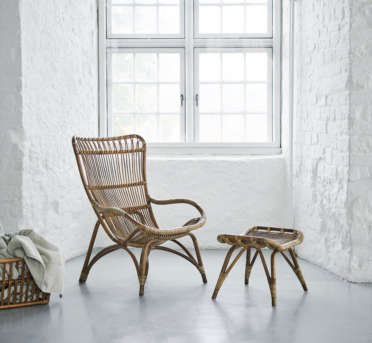 Dette er et livsstilsbillede af Monet Lounge Chair i antique rattan. I et rum med sommerfugletapet og dekorative marokkanske lanterner.