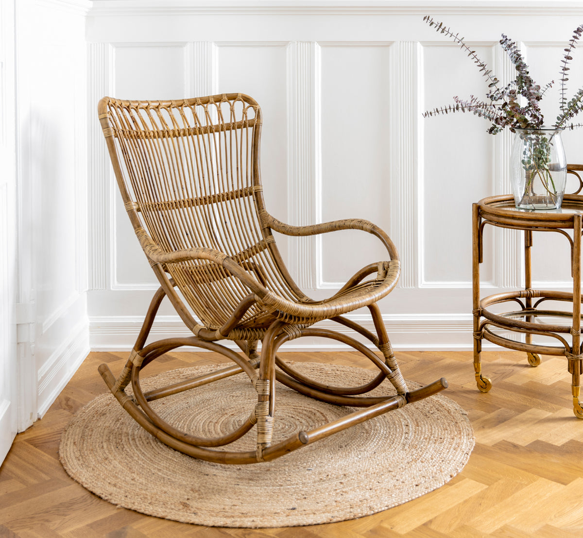 Dette er et livsstilsbillede af Romeo Rullebord i antique rattan. Stylet med hortensiaer og keramik mod en hvid murstensvæg.