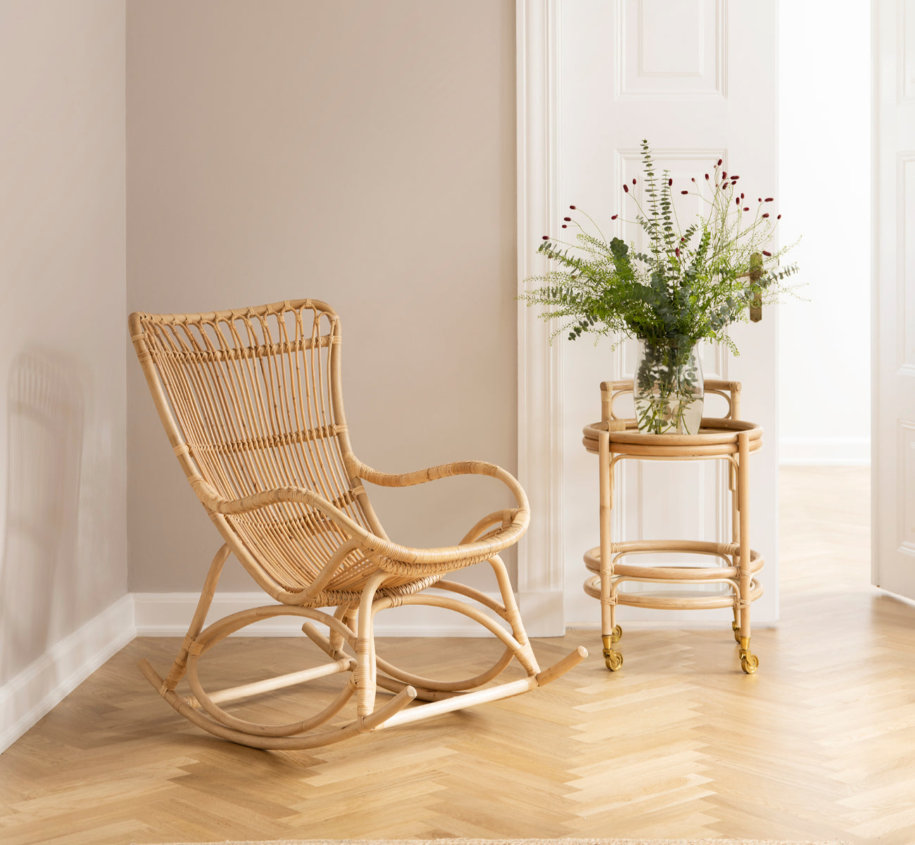 Dette er et livsstilsbillede af Romeo Trolley i natural rattan. Stylet med glas i et hyggeligt hjørne med sildebensgulv.