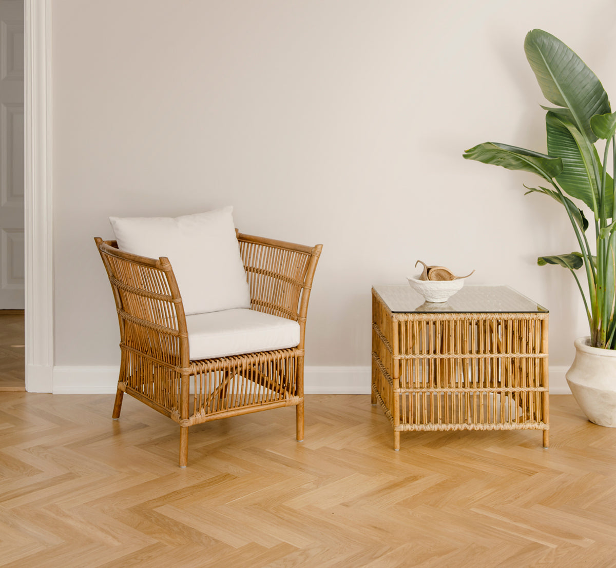 Dette er et livsstilsbillede af Donatello Sidebord i antique rattan, i et lyst interiør med hvide panelvægge og sildebensgulv.
