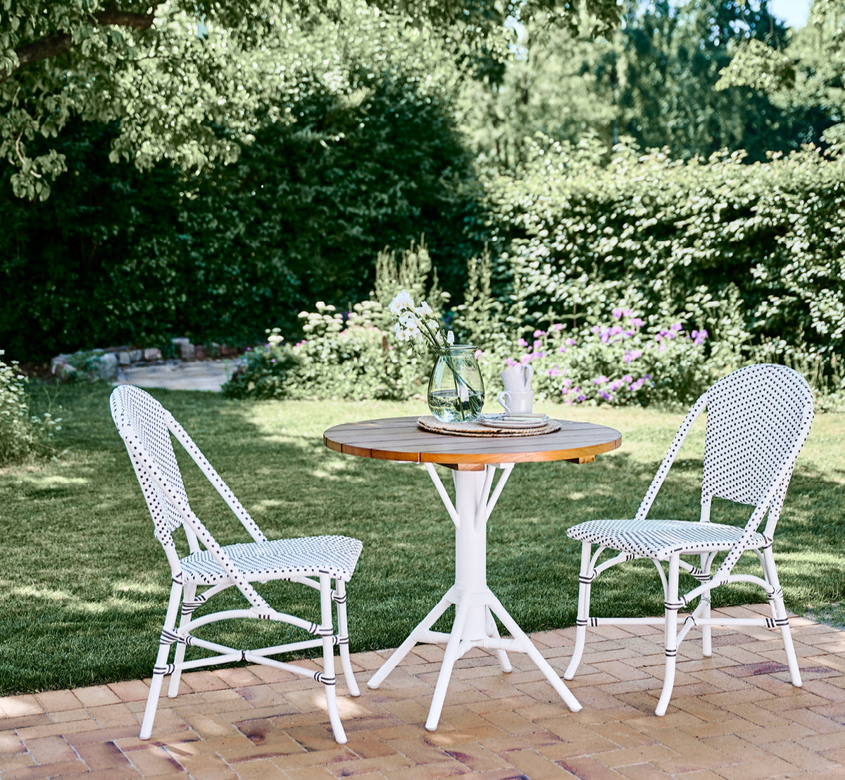 Dette er et livsstilsbillede af Sofie Udendørs spisebordsstol i white aluminium frame white w cappuccino dot artfibre.