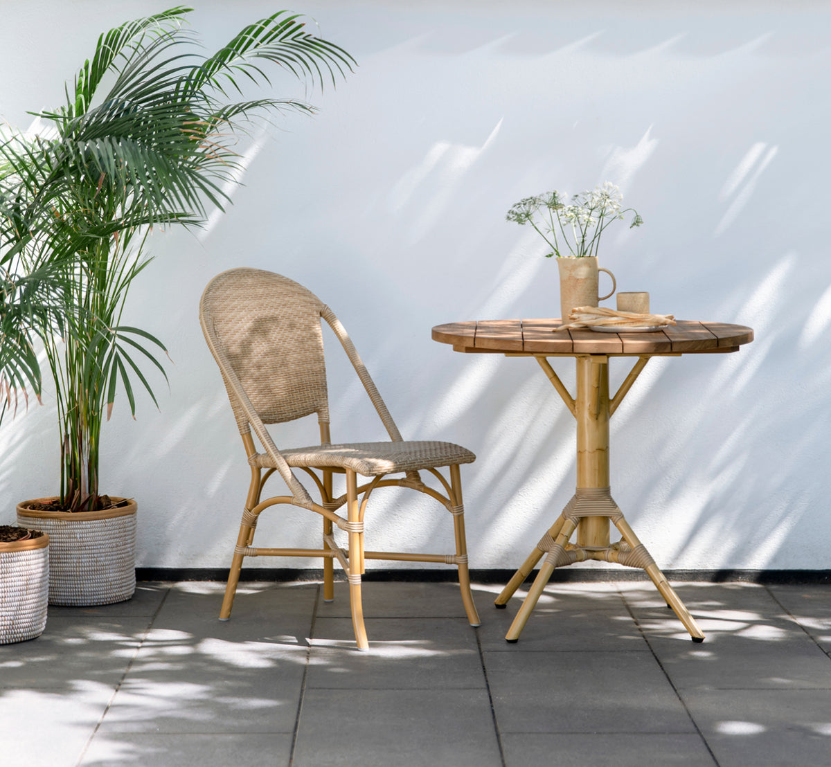Dette er et livsstilsbillede af Sofie Exterior Dining Chair i almond aluminium frame natural ArtFibre. På en middelhavsagtig terrasse.