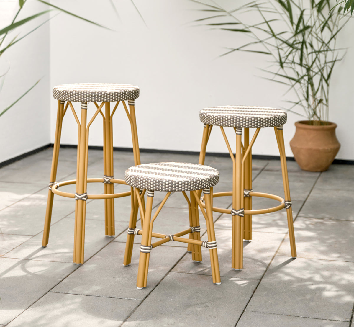 Dette er et livsstilsbillede af Simone Udendørs skammel i almond aluminium frame striped cappuccino ivory artfibre.