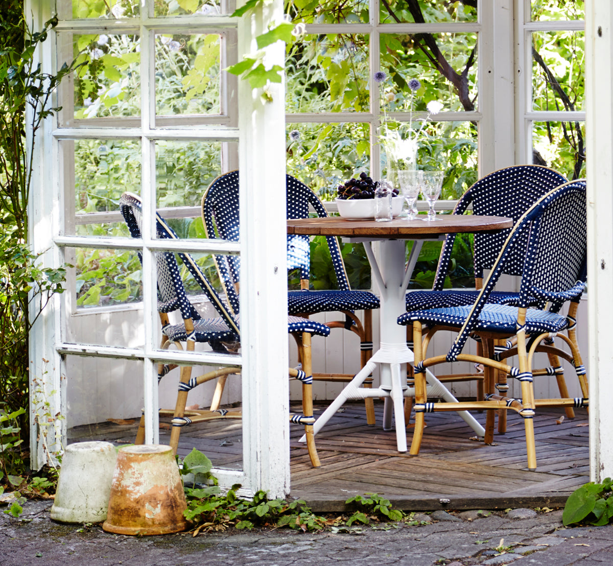 Dette er et livsstilsbillede af Sofie Spisebordsstol i navy blue w white dot artfibre skin on rattan frame. Stylet i et lyst interiør.