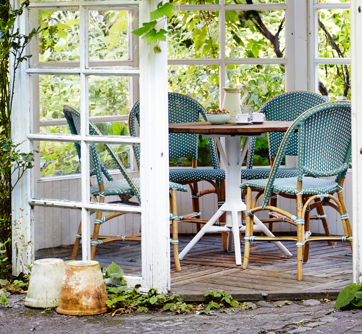 Dette er et livsstilsbillede af Sofie Spisebordsstol i salvie green w white dot artfibre skin on rattan frame. Stylet i et lyst interiør.