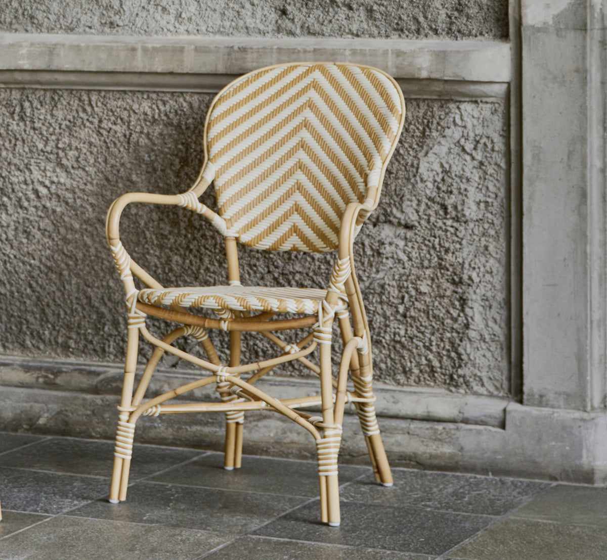 Dette er et livsstilsbillede af Isabell Spisestuelænestol i chevron Honey Ivory ArtFibre Skin on Rattan frame, i et lyst spiseområde med store.