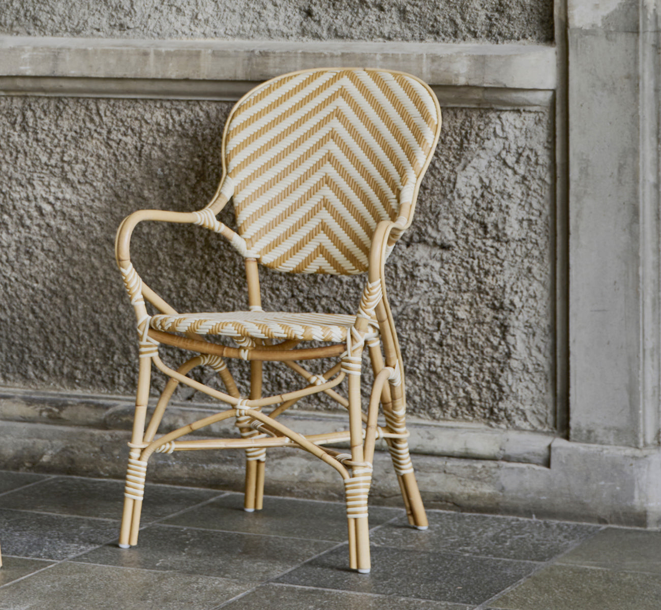 Dette er et livsstilsbillede af Isabell Spisestuelænestol i chevron Honey Ivory ArtFibre Skin on Rattan frame, i et lyst spiseområde med store.