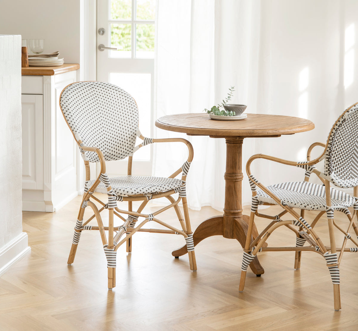 Dette er et livsstilsbillede af Isabell Spisestuelænestol i white w cappuccino dot ArtFibre Skin on Rattan frame, i et lyst spiseområde med store.