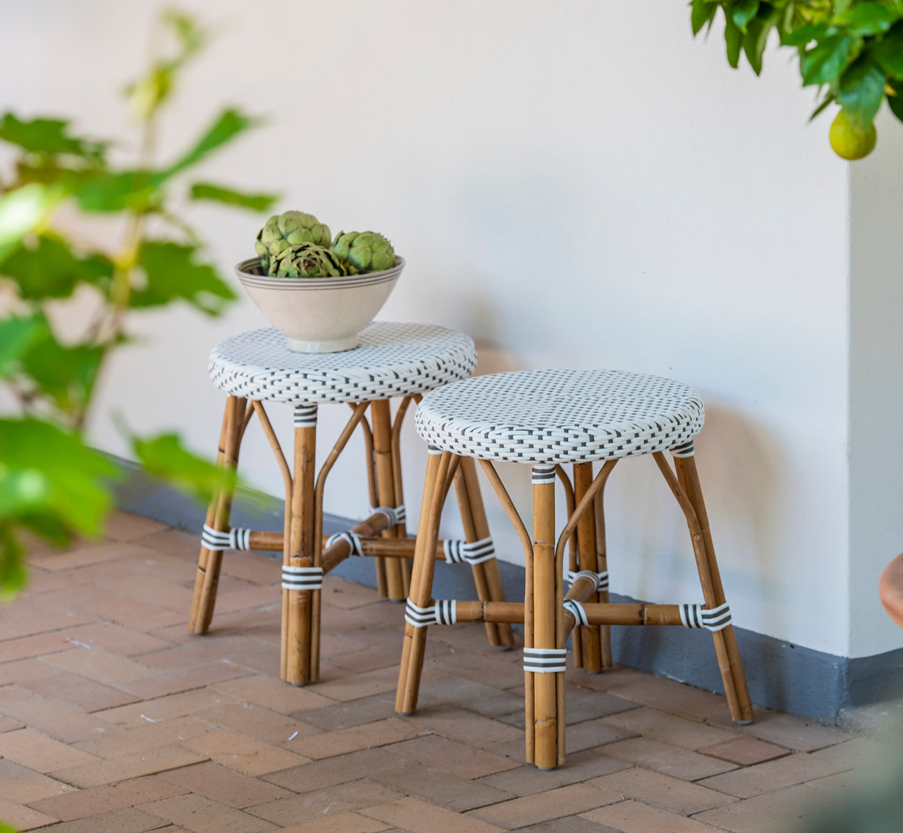 Dette er et livsstilsbillede af Simone Skammel i white w cappuccino dot ArtFibre Skin on Rattan frame. Et par på en murstensterrasse.