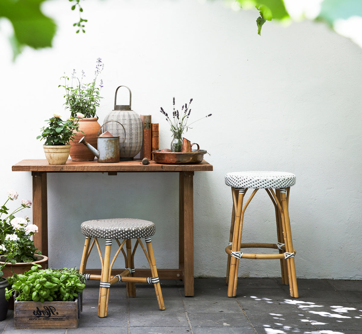 Dette er et livsstilsbillede af Simone Skammel i white w cappuccino dot ArtFibre Skin on Rattan frame. Ved et rustikt plantebord med planter.