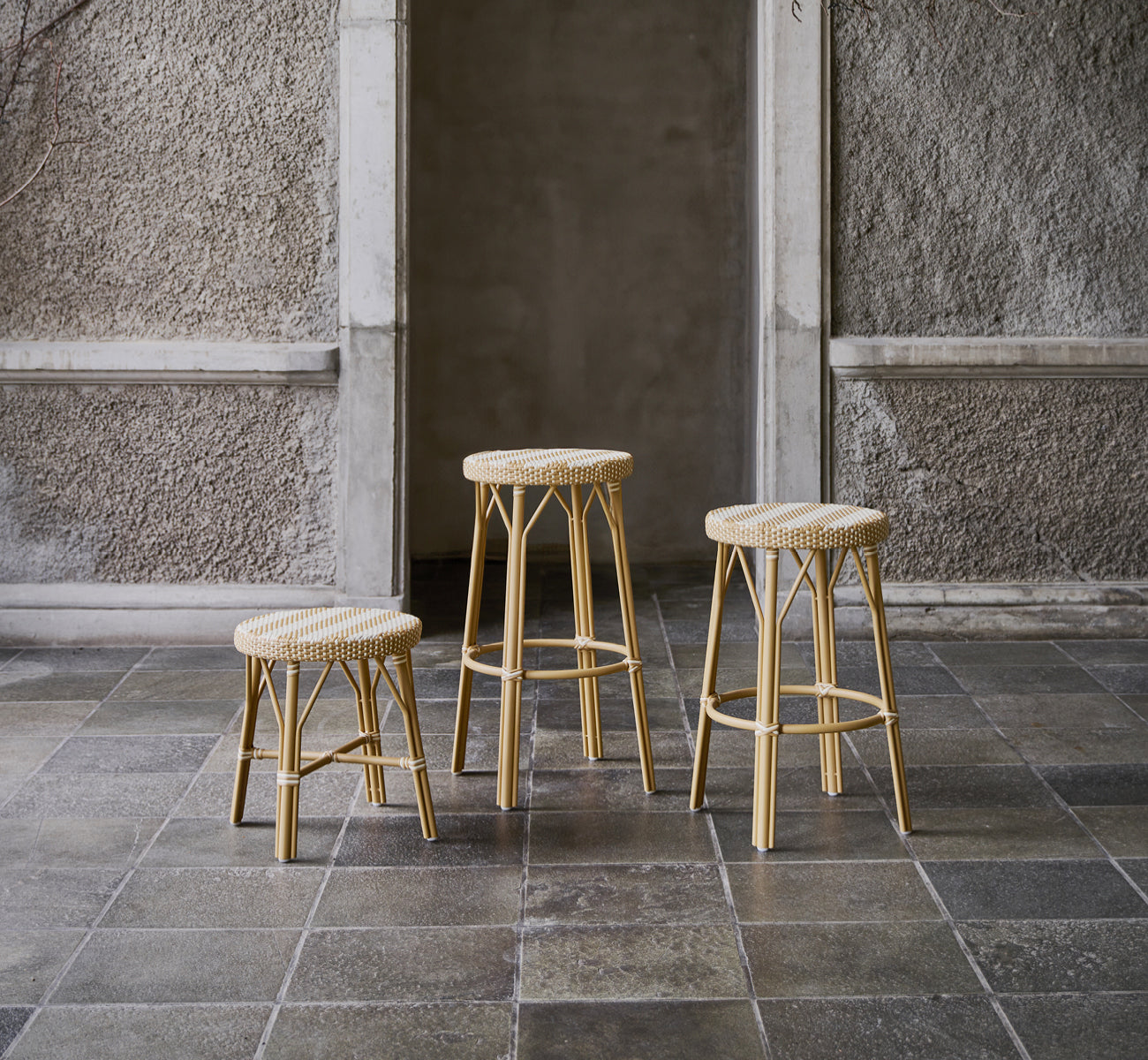 Dette er et livsstilsbillede af Simone Skammel i striped honey ivory ArtFibre Skin on Rattan frame. Vist i en stengårdhave.