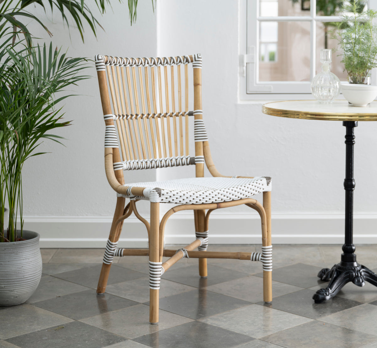 Dette er et livsstilsbillede af Monique Spisebordsstol i white w cappuccino dot artfibre skin on rattan frame. Stylet i et lyst interiør.