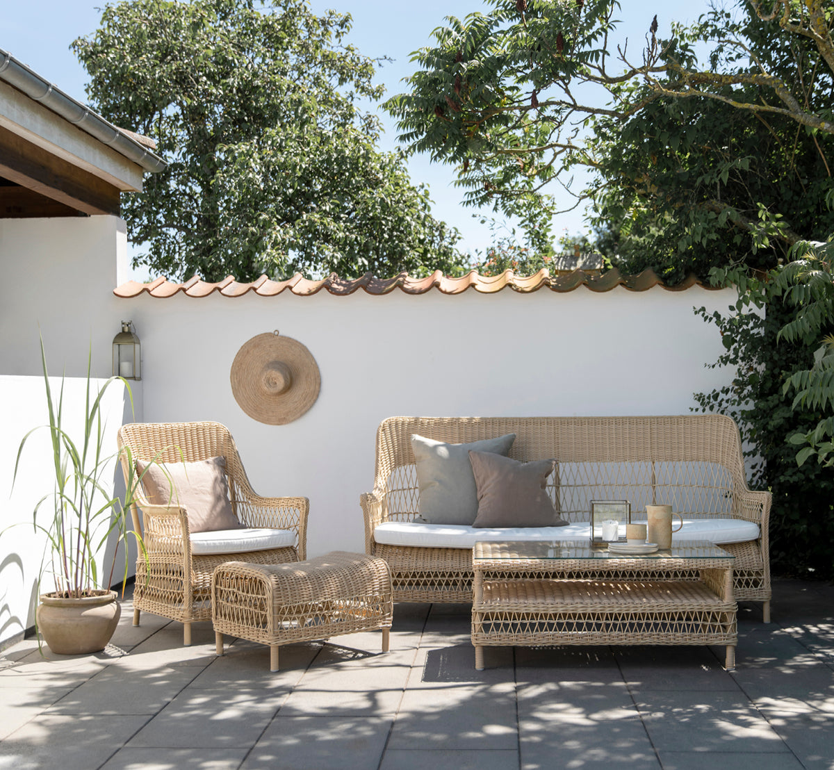 Dette er et livsstilsbillede af Dawn Sofa i natural ArtFibre Aluminium, på en kystterrasse med hvidt trædæk og havudsigt.