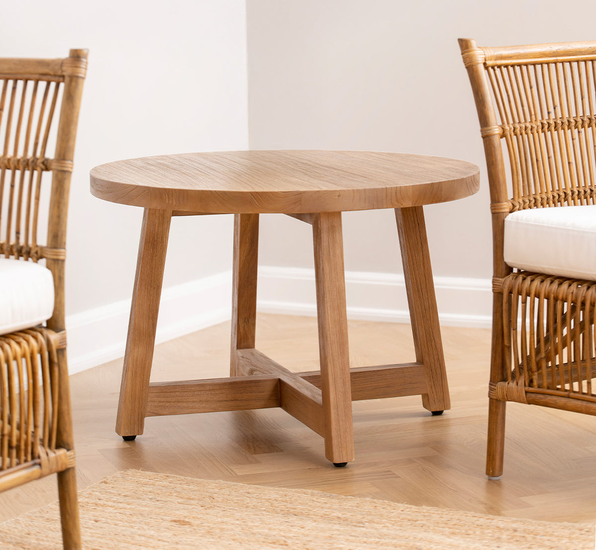 Dette er et livsstilsbillede af Aksel Sofabord i teak indoor, i et lyst interiør med sildebensgulv og rattanstole.