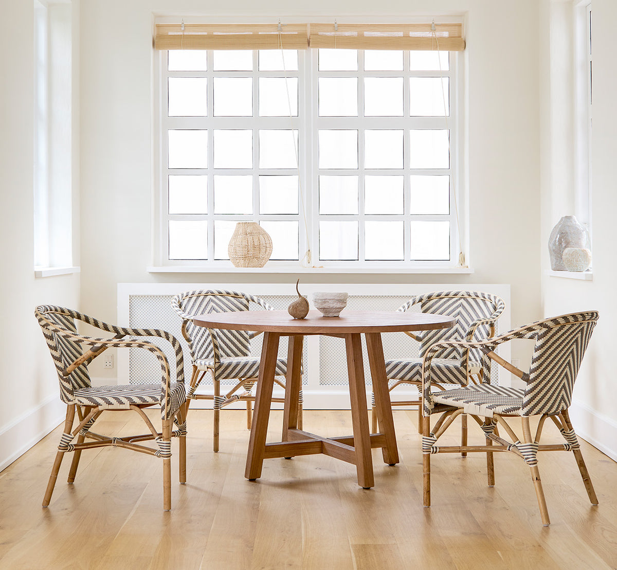 Dette er et livsstilsbillede af Aksel Spisebord i teak indoor, i et lyst spiseområde med store vinduer og lyst trægulv.