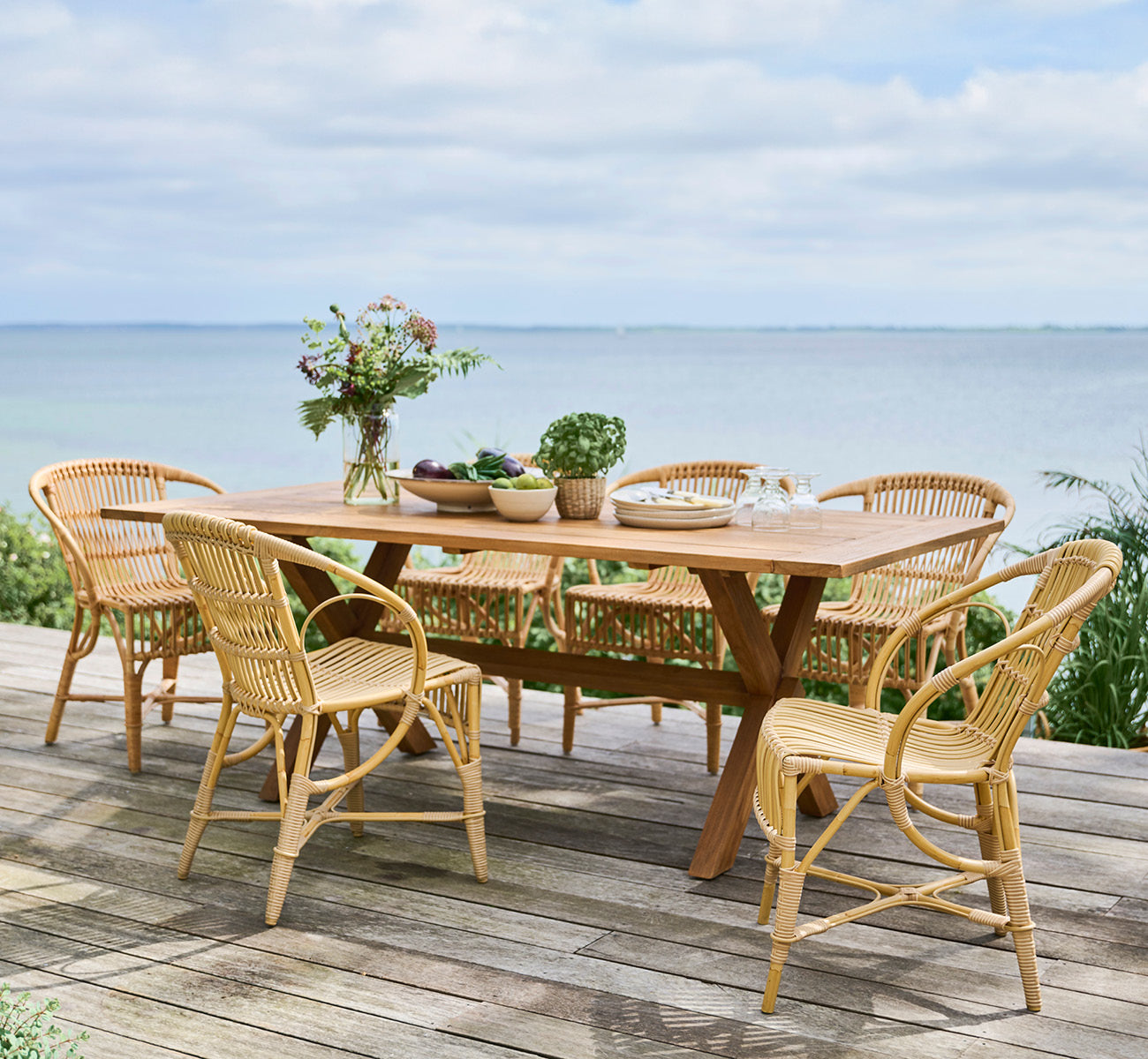 Dette er et livsstilsbillede af Colonial Bord 200 i outdoor Teak, på en strandterrasse med hvidt trædæk og havudsigt.