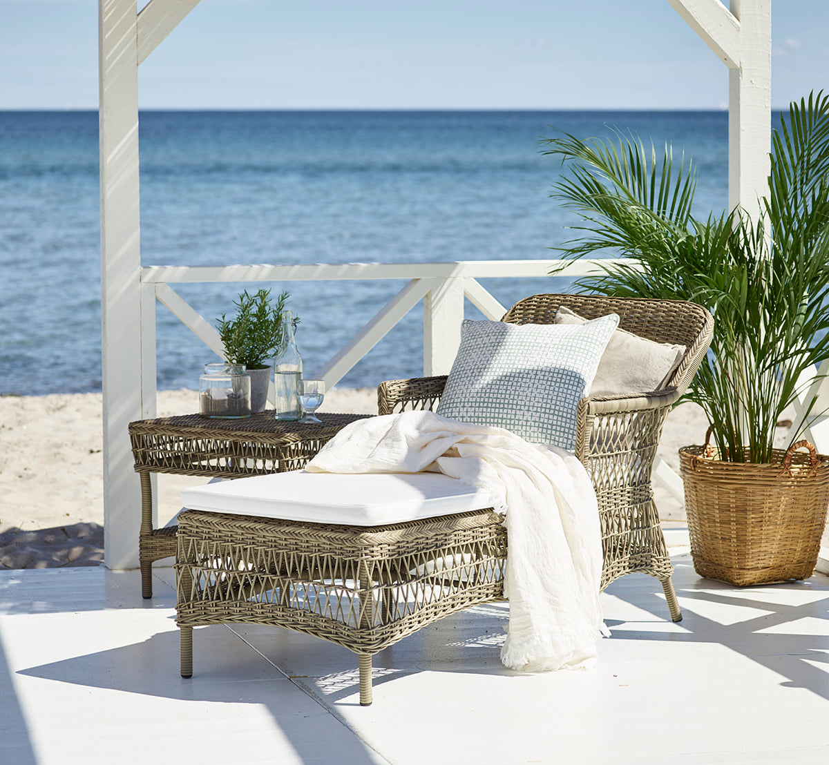Dette er et livsstilsbillede af Olivia Exterior Sunbed i antique grey artfibre aluminium. På en stenterrasse omgivet af have.