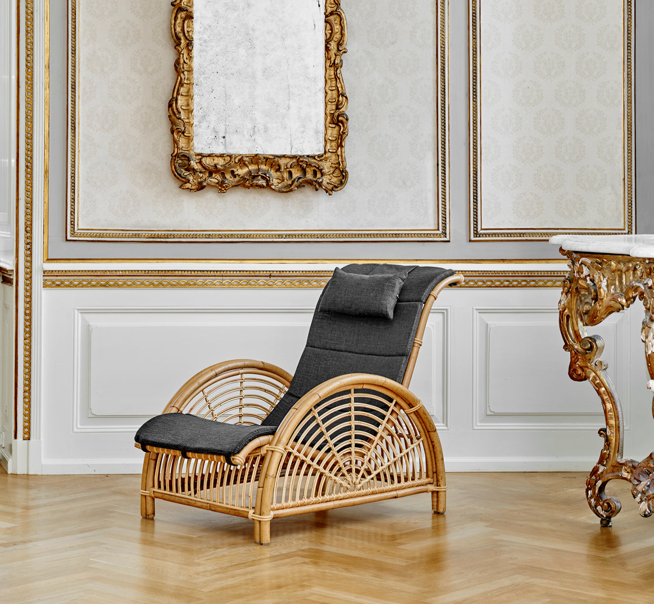 Dette er et livsstilsbillede af Paris Lænestol i polished natural rattan. Placeret på et sildebensparketgulv ved siden af en matchende bænk.