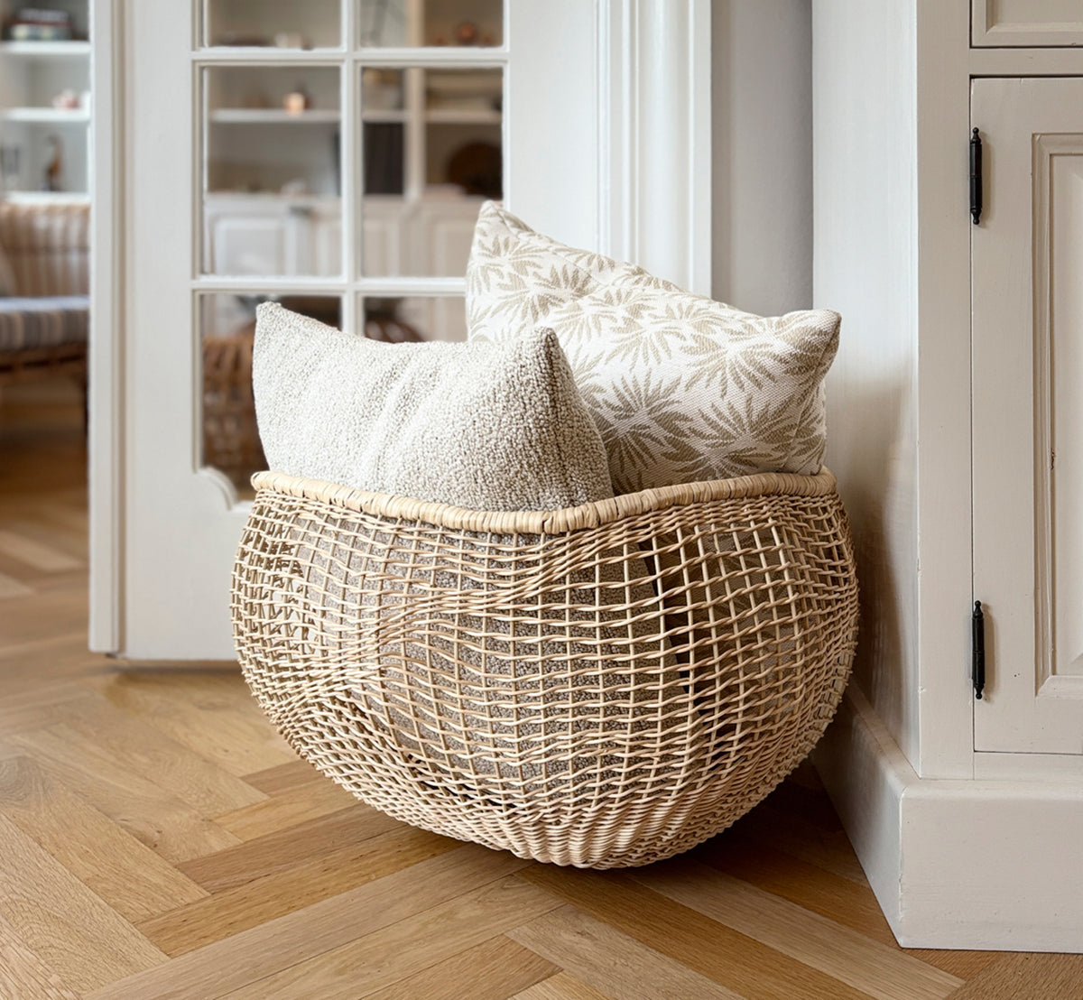 Dette er et livsstilsbillede af Folia Kurv i natural core weave iron frame, i et lyst hvidt interiør med lambrisering, stylet med tørrede blomster.