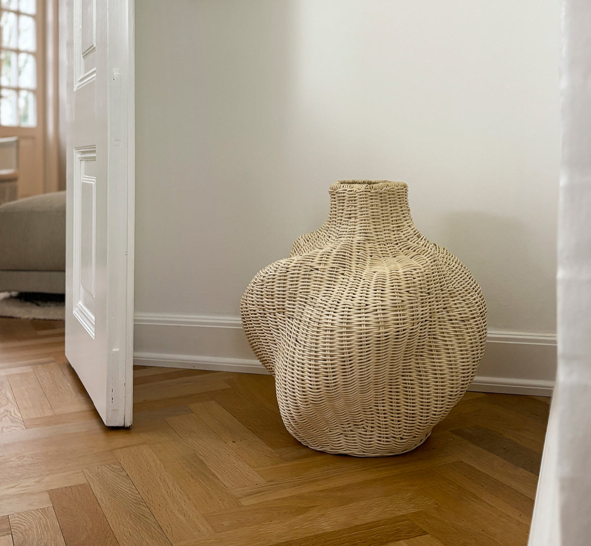 Dette er et livsstilsbillede af Solaris Basket Ø40 cm i natural core weave iron frame. Stylet med tørrede blomster ved en hvid dør på parketgulv.