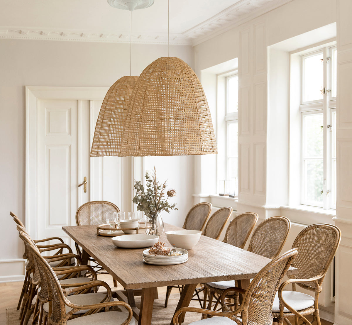 Dette er et livsstilsbillede af Showroom Lampeskærm i natural core weave artfibre & aluminium. Hængende over et dækket spisebord i et lyst rum.