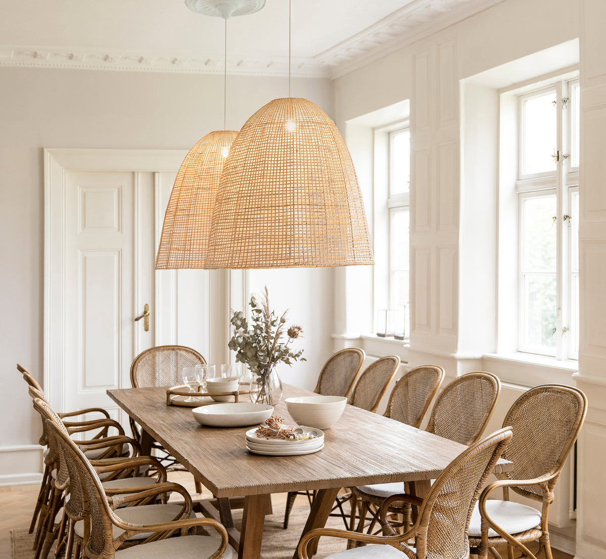 Dette er et livsstilsbillede af Showroom Lampeskærm i natural core weave artfibre & aluminium. Oplyser et spisebord med rattanstole nedenunder.