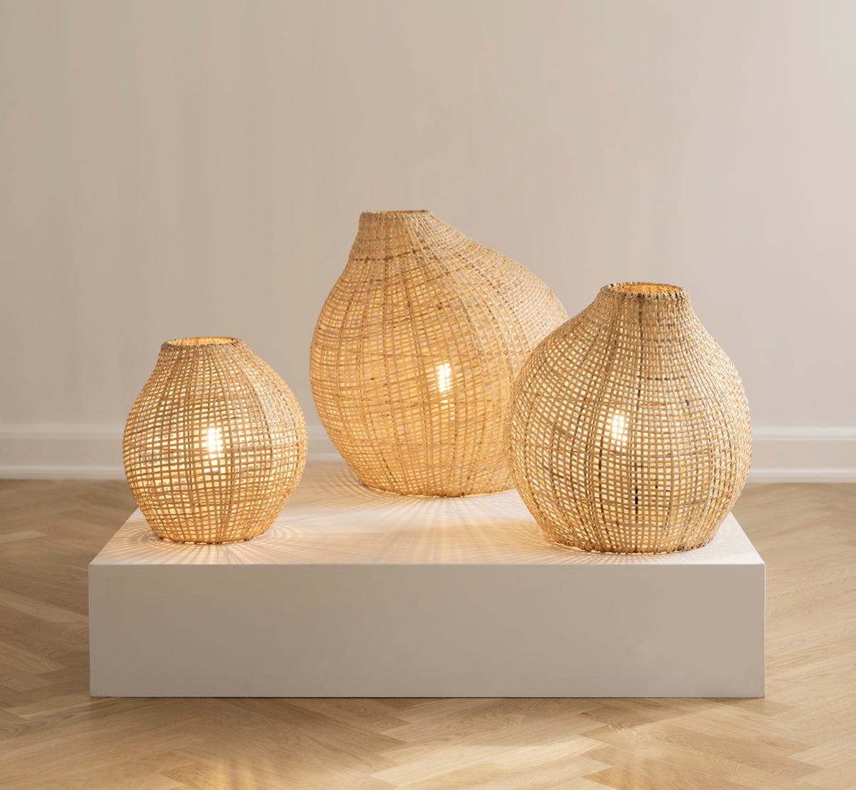 Dette er et livsstilsbillede af Figura Gulvlampeskærm i light natural weave rattan, udstillet på en hvid platform mod en neutral interiørbaggrund.