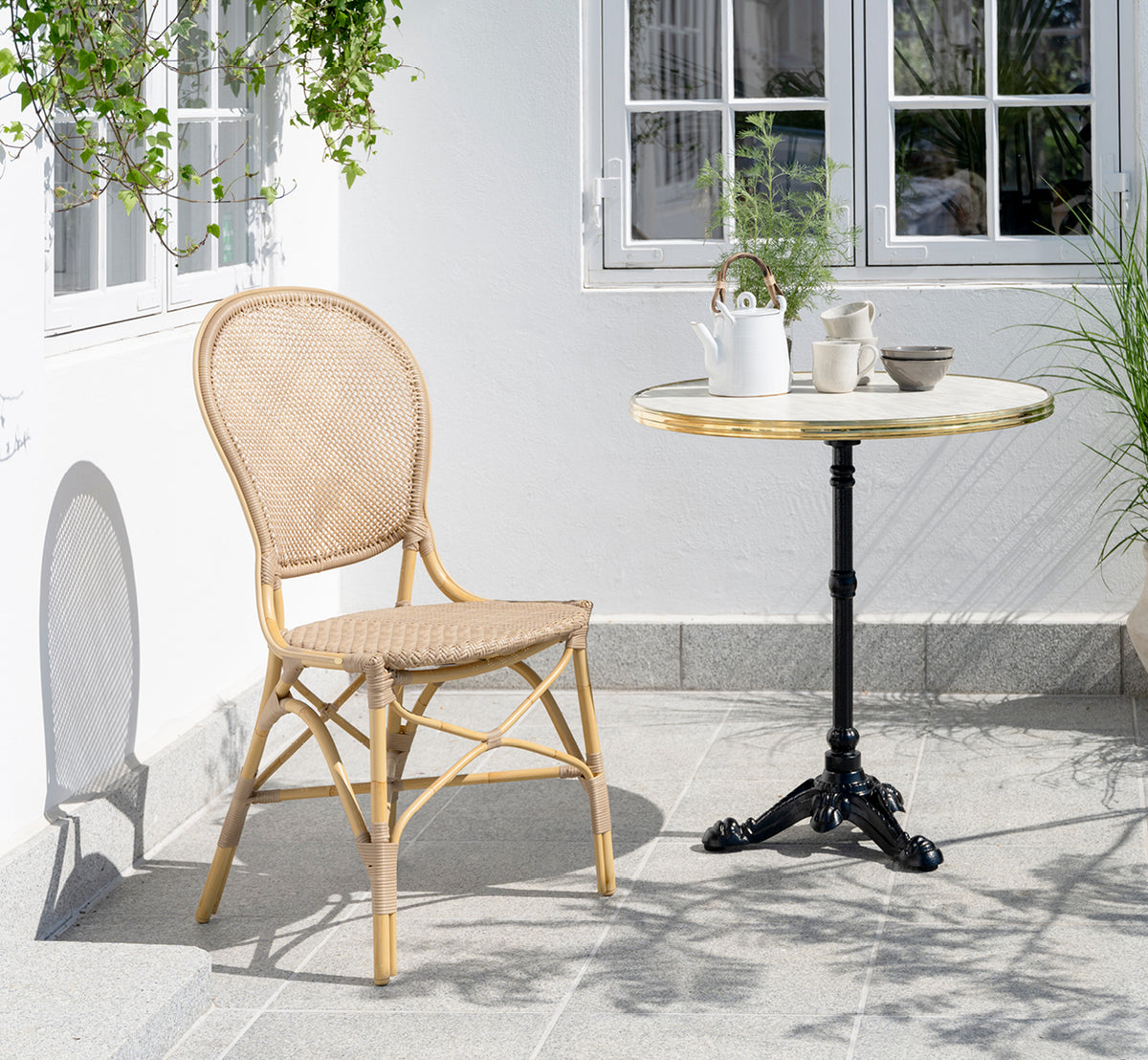Dette er et livsstilsbillede af Lyon Cafébord Versalite Marble Ø70 cm i cast iron. Gårdhave med spisestol og kaffesæt på bordet.