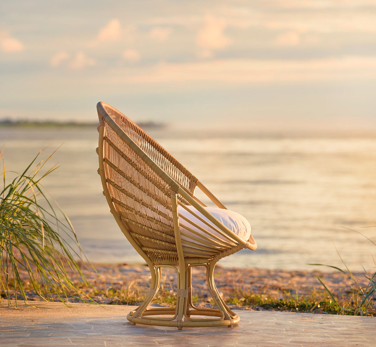 Dette er et livsstilsbillede af Luna Udendørs lænestol i natural aluminium artfibre. Placeret på stranden ved gyldent solnedgang med havet bagved.