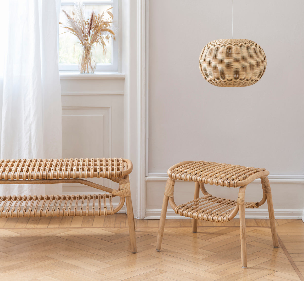 Dette er et livsstilsbillede af Machiya Bænk i natural skin on rattan. Skandinavisk rum med skammel, pendellampe og vase med pampasgræs.